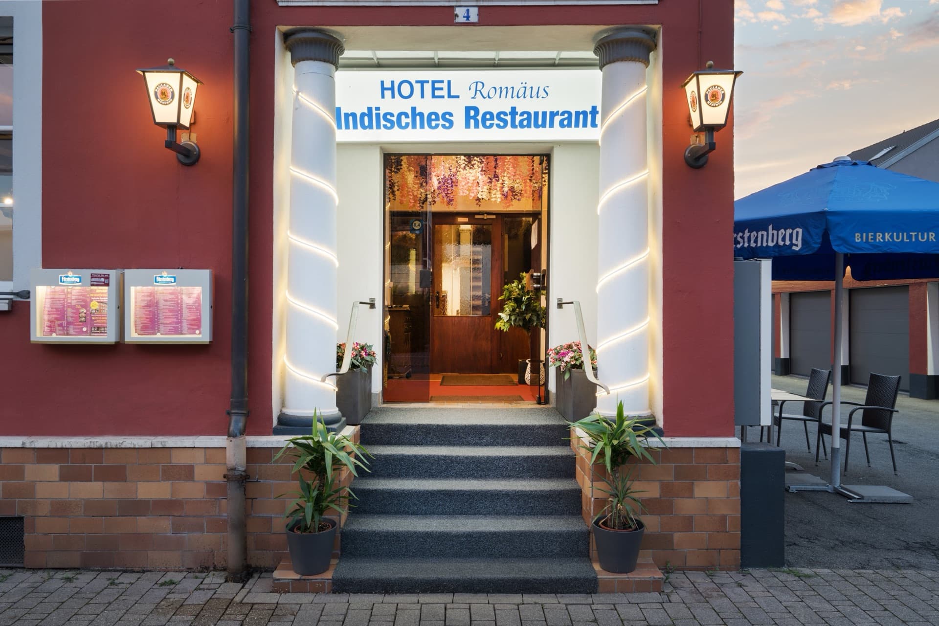 Beleuchteter Eingang des Hotel Romäus am Abend